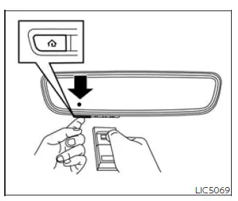 Hand-held transmitter positioned near a Nissan Murano HomeLink button for programming